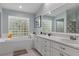 A Primary bath has a double sink vanity, soaking tub and a unique glass block window allowing natural light at 18816 Tracer Dr, Lutz, FL 33549