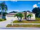 Charming single-story home with a well-manicured front yard and mature palm trees on a sunny day at 19709 Wyndham Lakes Dr, Odessa, FL 33556