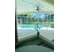 Screened-in pool area features tropical landscaping and serene water views from inside the home at 19709 Wyndham Lakes Dr, Odessa, FL 33556