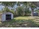 A backyard features a metal storage shed, a large shade tree, and mature landscaping at 2004 Windsor Way, Tampa, FL 33619