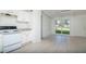 A view of the kitchen with white cabinets and appliances opening to the dining area at 2004 Windsor Way, Tampa, FL 33619