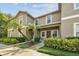 Exterior shot of a two-story condo featuring lush landscaping and a covered entryway with palm trees at 2347 Willimette Dr, Wesley Chapel, FL 33543