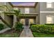 Charming two-story condo featuring lush landscaping, including palm trees, and a covered front porch at 2347 Willimette Dr, Wesley Chapel, FL 33543