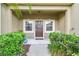 Inviting front porch with a brown front door framed by sidelight windows and manicured greenery at 2347 Willimette Dr, Wesley Chapel, FL 33543
