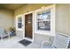 Close-up of the front porch with a brown door, sidelight windows, and seating at 2347 Willimette Dr, Wesley Chapel, FL 33543