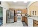 Full kitchen featuring stainless steel refrigerator, white oven, and wood cabinets with tiled floors at 2347 Willimette Dr, Wesley Chapel, FL 33543