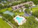 An aerial view that showcases a sparkling community pool, tennis court, and lush landscaping in this desirable neighborhood at 3044 Red Oak Ct # 204, Palm Harbor, FL 34684