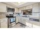 Bright kitchen featuring stainless steel appliances, white cabinets, and a window to the living space at 3055 Casa Del Sol Cir # 202, Clearwater, FL 33761