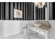 Chic powder room featuring black and white striped wallpaper and marble vanity at 3125 Christophers Watch Ln, Ruskin, FL 33570