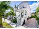 Charming two-story white home with a front porch, showcasing meticulous landscaping and a brick driveway at 340 6Th E St, Bradenton, FL 34208
