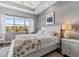 This main bedroom features tray ceilings, wood-look floors, and a bright window with neighborhood views at 340 Sapphire Lake Dr # 202, Bradenton, FL 34209