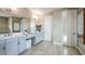 Bright bathroom featuring a double vanity with quartz countertops and white cabinets, complemented by neutral tile floors and modern lighting at 3411 Lumber Falls Dr, Plant City, FL 33565