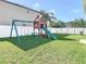 Green backyard featuring a modern playhouse swing set with slide at 3512 Gerrads Cross Ct, Land O Lakes, FL 34638