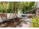 Tropical backyard with a wooden deck and seating, a fire pit, dining table, shed, and lush landscaping at 3620 W San Pedro St, Tampa, FL 33629