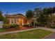 Charming bungalow-style home with inviting front porch, lush landscaping, and walkway, illuminated by warm exterior lighting at dusk at 3620 W San Pedro St, Tampa, FL 33629