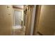 Hallway view of a bathroom with tile floors, glass shower doors, oak cabinetry, and wallpaper at 7111 Oregon Chickadee Rd, Weeki Wachee, FL 34613