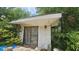 Close-up of a detached building showing weathered facade, a wood-framed door, and surrounding vegetation at 7111 Oregon Chickadee Rd, Weeki Wachee, FL 34613