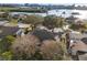 Aerial view of rooftops, lush greenery, and a peek at a backyard pool surrounded by tall trees at 8083 Bayhaven Dr, Seminole, FL 33776
