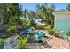 Backyard featuring a brick patio with a fire pit and chairs, complemented by lush landscaping for outdoor enjoyment at 905 8Th Sw Ave, Largo, FL 33770
