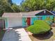 Charming turquoise house featuring a red door, green shrubbery and a well-manicured lawn at 905 8Th Sw Ave, Largo, FL 33770