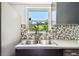 Well-lit kitchen sink with a view from the large window and a decorative tile backsplash at 905 8Th Sw Ave, Largo, FL 33770
