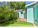 A view of the home's side yard showcasing tropical plants, artificial turf, and charming curb appeal at 905 8Th Sw Ave, Largo, FL 33770