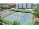 Aerial view of well-maintained tennis courts next to a condo building and parking area at 10216 Regal Dr # 310, Largo, FL 33774