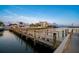 Picturesque waterfront scene with a dock, palm trees, and reflections on the calm water at sunset at 10216 Regal Dr # 310, Largo, FL 33774