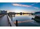Picturesque waterfront view featuring a dock and buildings reflecting on the calm water at sunset at 10216 Regal Dr # 310, Largo, FL 33774