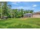 Large backyard featuring a screened-in lanai, lush greenery, and ample space for outdoor activities at 10305 Worthy Lamb Way, New Port Richey, FL 34654