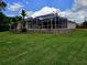 Expansive backyard featuring lush green lawn, mature trees, and a screened-in patio for outdoor living at 10305 Worthy Lamb Way, New Port Richey, FL 34654