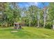 Spacious backyard features a charming wooden gazebo and ample green space surrounded by mature trees for privacy at 10305 Worthy Lamb Way, New Port Richey, FL 34654