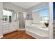 Bright bathroom with walk-in shower, garden tub, and white cabinets with hardwood floors at 10305 Worthy Lamb Way, New Port Richey, FL 34654