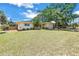 Wide exterior shot showcasing a well-maintained property with a spacious front yard and a yellow home with a blue accent at 11376 119Th Ter, Largo, FL 33778