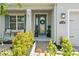 Inviting front porch with seating area, lush landscaping, and a decorative wreath on the front door at 11742 Lake Lucaya Dr, Riverview, FL 33579