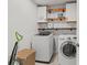 Laundry room with front load machines, open shelving, and accent wall at 11742 Lake Lucaya Dr, Riverview, FL 33579