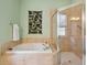 Bathroom featuring a soaking tub, glass-enclosed shower and tasteful tile accents at 12435 Oak St, San Antonio, FL 33576