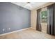 Bright, cozy bedroom with a gray accent wall, tile floors, and window with neutral curtains at 12435 Oak St, San Antonio, FL 33576