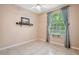 Neutral bedroom with tile floors, a window with sheer curtains, and decorative shelf at 12435 Oak St, San Antonio, FL 33576