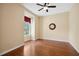 Bedroom featuring hardwood floors, a ceiling fan, a window with decorative curtains, and a wall clock at 12435 Oak St, San Antonio, FL 33576