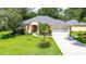 Lovely home with a well-maintained lawn, mature trees, and a three-car garage, and a welcoming red door at 12435 Oak St, San Antonio, FL 33576