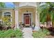 Charming front entrance with red door, decorative wreath, and inviting walkway with garden plants at 12435 Oak St, San Antonio, FL 33576