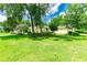Home featuring a lush green lawn, mature trees, and colorful landscaping at 12435 Oak St, San Antonio, FL 33576