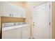 Practical laundry room with washer, dryer, overhead cabinets, and access door to the outdoors at 12435 Oak St, San Antonio, FL 33576