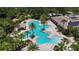 Aerial view of a community pool featuring multiple pools, a clubhouse, palm trees, and ample seating at 12443 Adventure Dr, Riverview, FL 33579