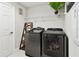 Laundry room with modern gray washer and dryer, a wooden step ladder and white shelving at 12643 Horseshoe Bend Dr, Lithia, FL 33547
