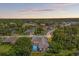 Aerial view of a home with a screened pool in a lush, green neighborhood at twilight at 13375 Newcastle Ave, Spring Hill, FL 34609