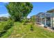 Green backyard features trees, bushes, and a screened-in patio area at 13375 Newcastle Ave, Spring Hill, FL 34609