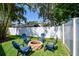 The fenced backyard offers a fire pit with seating, green grass, and lush trees at 1622 El Tair Trl, Clearwater, FL 33765