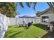 The backyard features a fire pit with chairs, a white fence, green grass, and trees at 1622 El Tair Trl, Clearwater, FL 33765